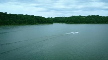 Following small recreational yellow speedboat sliding over Taylorsville lake water surface