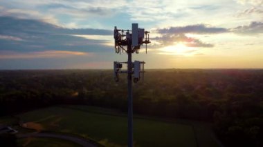 Morning sun is flashing through openings between wireless repeating equipment devices of a tower on a top of a park hill in Central Kentucky
