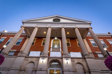 Woodford county courthouse in Versailles, Kentucky as seen from the sidewalk in front of it during early morning hours with lights still shining.