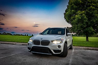 Lexington, Kentucky ABD - Sep 7 2022: Beyaz BMW X1, gün batımında Jacobson Gölü 'nün kıyısında bir çimenliğin önünde, ufukta ay varken..