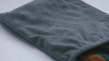 Beyaz arka planda kumaş torbasından dökülen dikiş malzemeleri ortaya çıkıyor.