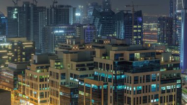 Körfez Meydanı Bölgesi gece zaman dilimi. Karışık kullanım ve Dubai 'deki Business Bay' de bulunan düşük katlı kompleks ofis binaları. Parlayan pencerelerle yukarıdan hava görüntüsü