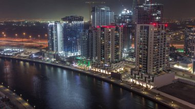 Dubai, Birleşik Arap Emirlikleri 'ndeki Business Bay hava sahasındaki gece kuleleri. Kanalla yukarıdan inşaat alanı görünümü