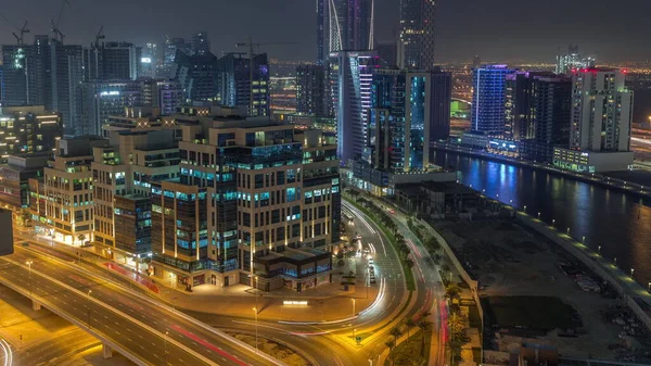 Körfez Meydanı Bölgesi gece zaman dilimi. Karışık kullanım ve Dubai 'deki Business Bay' de bulunan düşük katlı kompleks ofis binaları. Yukarıdan hava manzaralı ve yolda trafik var.