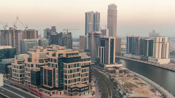 Körfez Meydanı bölgesinden geceye geçiş zamanı. Karışık kullanım ve Dubai 'deki Business Bay' de bulunan düşük katlı kompleks ofis binaları. Yukarıdan hava manzaralı ve yolda trafik var.