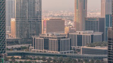 Şehir merkezindeki gökdelenler, metro hattı üstgeçidi ve trafik zaman ayarlı. Gün batımından önce kuleleri olan gökyüzü manzarası. Dubai, Birleşik Arap Emirlikleri