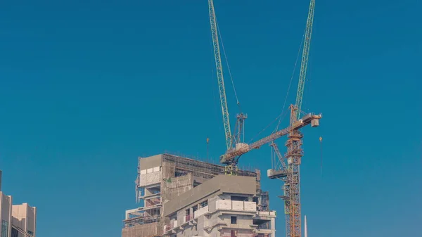 現代の建設現場で働くクレーンは 新しい超高層ビルのタイムラプスの作品 都市開発の迅速な成果と活動の構築 — ストック写真