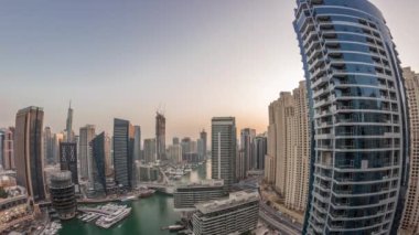 Kanal çevresindeki Dubai marina gökdelenlerine gün be gece yüzen teknelerle hava görüntüsü