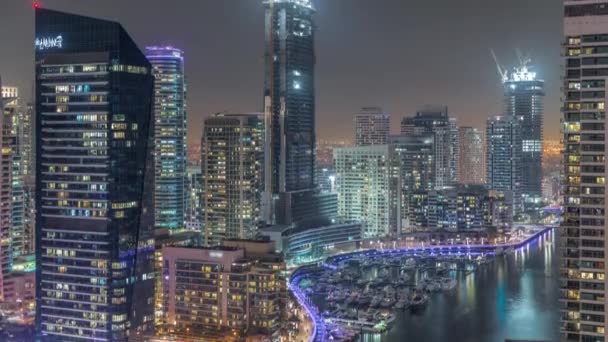 Вид с воздуха на пристань для яхт Дубая небоскребы вокруг канала с плавучих лодок ночное время — стоковое видео