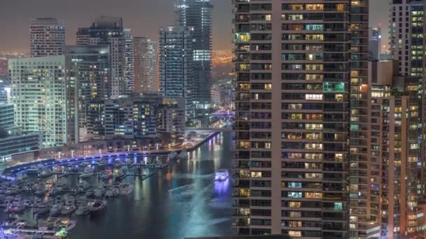 Flygfoto över Dubai marina skyskrapor runt kanalen med flytande båtar natt timelapse — Stockvideo