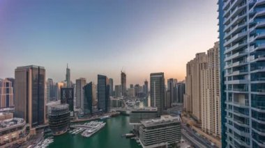 Kanal çevresindeki Dubai marina gökdelenlerine gün be gece yüzen teknelerle hava görüntüsü