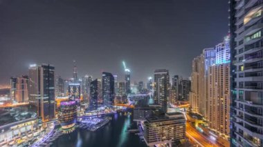 Kanal çevresindeki Dubai marina gökdelenlerine tüm gece yüzen teknelerle hava görüntüsü