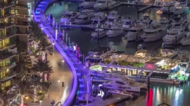 Kanal çevresindeki Dubai yat limanının hava görüntüsü ve gece vakti yüzen tekneler.