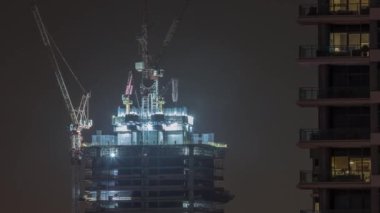 Gökdelen yapım aşamasında vinçler ve demir çerçeve gece zaman ayarlı.