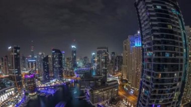 Kanal çevresindeki Dubai marina gökdelenlerine tüm gece yüzen teknelerle hava görüntüsü