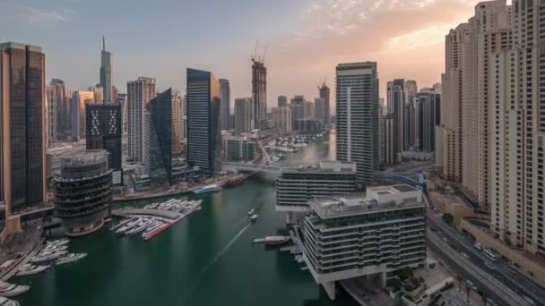 Вид с воздуха на небоскребы гавани Дубая вокруг канала с плавучими лодками день и ночь — стоковое видео