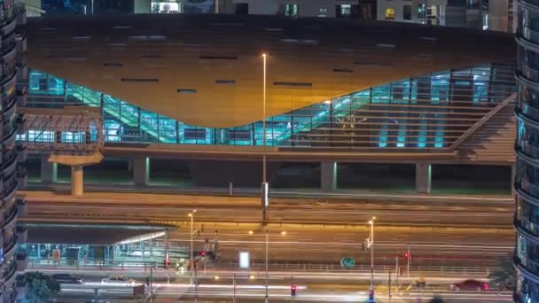 Traffico all'incrocio vicino alla fermata del tram e uscita dalla stazione della metropolitana su uno sfondo nel porto turistico di Dubai timelapse notte aerea — Video Stock