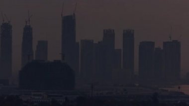 Dubai Creek Limanı 'nda gün doğumu gökdelenler ve inşaat halindeki kulelerle birlikte.