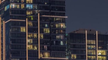 Gece vakti apartmanların pencereleri, evlerin pencerelerinden gelen ışık.