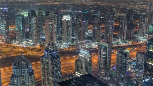 Dubai Marina e JLT distrito com tráfego na estrada entre arranha-céus aéreo noite timelapse. — Vídeo de Stock