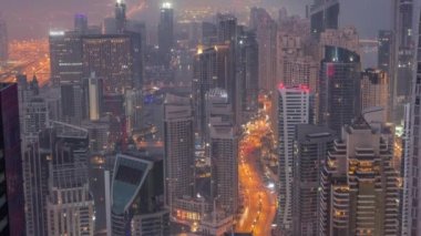 Dubai Marina 'nın kıyı şeridi boyunca gece gündüz gökdelenlerle çevrili kanalı görüntüsü. Dubai, BAE