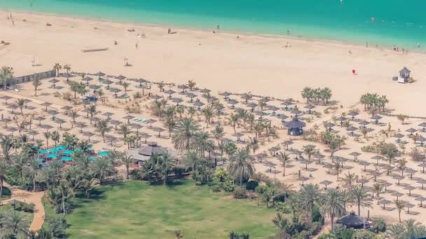 Натовп JBR пляж з туристами, які насолоджуються сонцем і морем, сидячи під парасолевим виглядом з висоти таймелапсу. — стокове відео