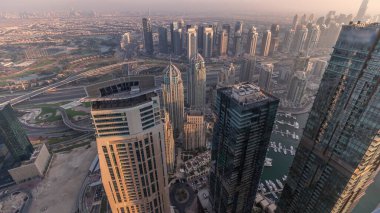 Dubai Marina Panorama 'sı JLT gökdelenleri ve golf sahası zaman çizelgesiyle gün batımında, Dubai, Birleşik Arap Emirlikleri. Yukarıdaki kulelerden hava görüntüsü. Bulanık hava ile şehir silüeti
