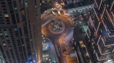 Gökdelenler arasında büyük bir zaman diliminde daire şeklinde bir yol kesişiminin havadan görünüşü. BAE 'nin Dubai Marina bölgesinin şehir manzarası. Arabaları ve süpermarketin yanındaki park yeri var.