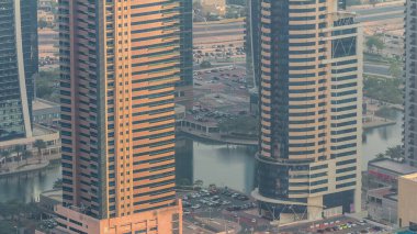 Dubai lüks konut bölgesinde hafif araçlar için park yeri, yukarıdan hava manzaralı. Akşam turuncu ışıklı JLT gökdelenleri