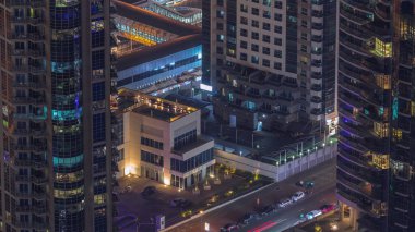 Gökdelenler ve büyük bir zaman diliminde park yeri arasındaki yol kesişiminin havadan görüntüsü. BAE 'nin Dubai Marina bölgesinin şehir manzarası. Arabaları ve pencereleri olan lüks kuleleri var.