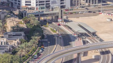 Dubai Marina 'daki tramvay istasyonunda, yaya köprüsü hava saatleri var. Kavşakta ve üstgeçitte trafik var. Yukarıdan görüntüle