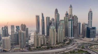 Dubai Marina 'nın gökdelenleri gün batımından sonra gün batımından sonra trafik varken gece gündüz en yüksek konut binaları aydınlatılıyor. JLT bölgesinden hava üst görünümü