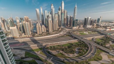 Dubai Marina karayolu kavşağı spagetti kavşağı zaman dilimi. Arka planda uzun gölgeler olan en uzun gökdelenler. JLT bölgesinin hava üst görüntüsü