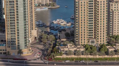 Yatı yüzen gökdelenler ve tekneler arasındaki kavşağın hava görüntüsü. BAE 'nin Dubai Marina bölgesinin şehir manzarası. Çeşmenin etrafında arabalar ve palmiyeler var.