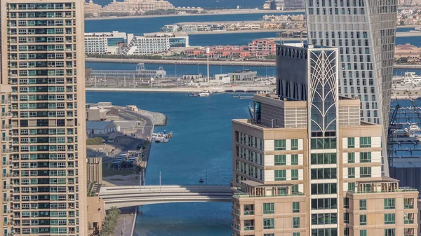 Dubai Marina 'daki gezinti güvertesi ve kanalı. Zaman çizelgesi etrafında lüks gökdelenler var. Birleşik Arap Emirlikleri. Yatlar ve tekneler yukarıdan Palm Island 'a kadar havadan görünüyor.