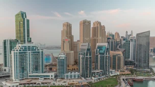 Dubai Marina with several boat and yachts parked in harbor and skyscrapers around canal aerial day to night timelapse. — Stock Video