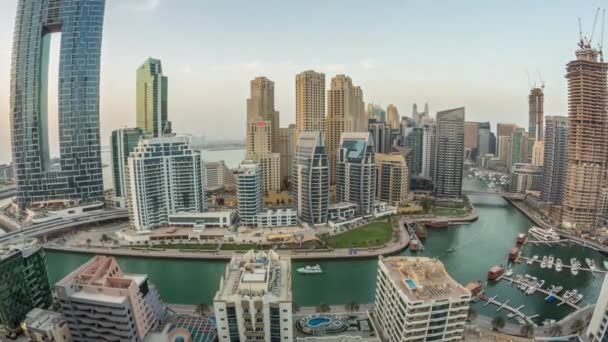 Великолепный вид на Dubai Marina с несколькими лодками и яхтами, припаркованными в гавани и небоскребами вокруг канала днем и ночью. — стоковое видео