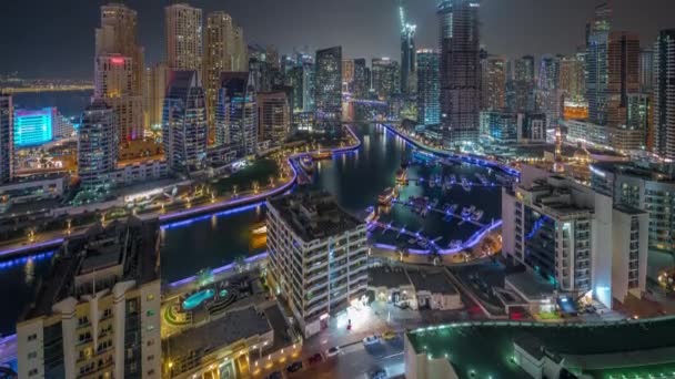 Dubai Marina con diverse barche e yacht parcheggiati in porto e grattacieli intorno al canale aereo notte timelapse. — Video Stock