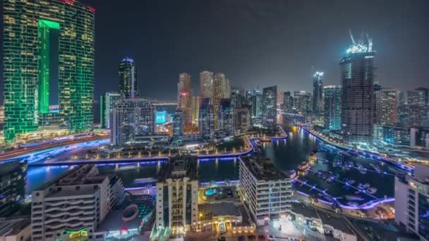 Dubai Marina avec plusieurs bateaux et yachts garés dans le port et gratte-ciel autour du canal timelapse de nuit aérienne. — Video