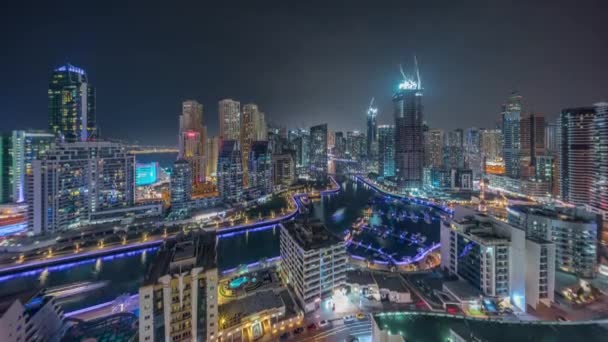 Dubai Marina with several boat and yachts parked in harbor and skyscrapers around canal aerial night timelapse. — Stock Video