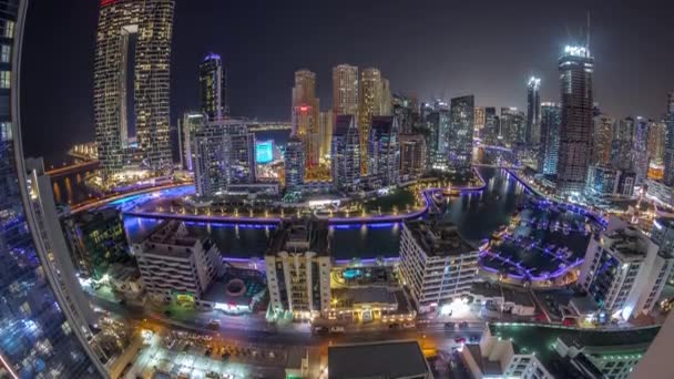 Panorama de Dubai Marina con varios barcos y yates estacionados en el puerto y rascacielos alrededor del canal de la noche aérea timelapse. — Vídeos de Stock