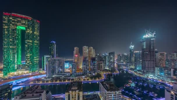 Dubai Marina with several boat and yachts parked in harbor and skyscrapers around canal aerial all night timelapse. — Stock Video