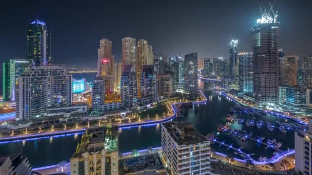 Dubai Marina con diverse barche e yacht parcheggiati in porto e grattacieli intorno aerea canale tutta la notte. — Video Stock
