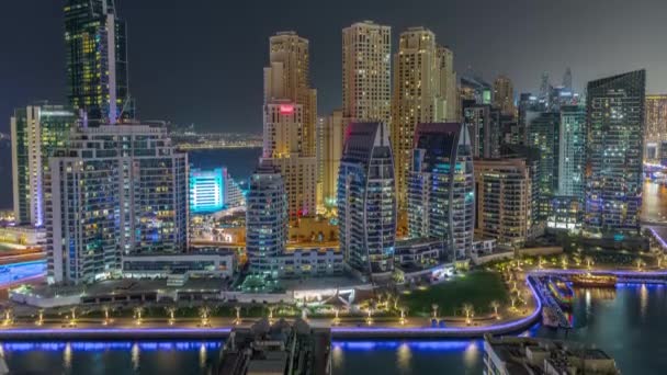 Dubai Marina avec plusieurs bateaux garés près du front de mer et gratte-ciel autour du canal timelapse de nuit aérienne. — Video