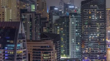 Dubai Marina 'daki modern gökdelenler, birçok aydınlatmalı pencereye yakın çekim gece zaman çizelgesi.