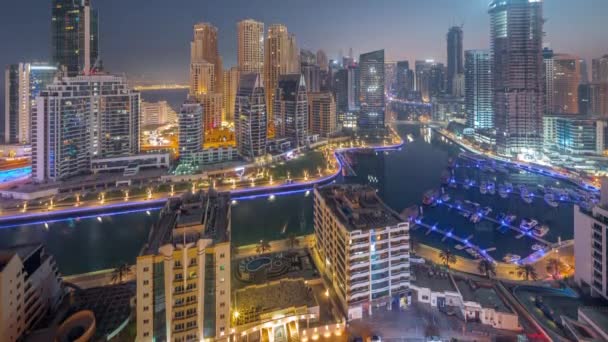 Dubai Marina с несколькими лодками и яхтами, припаркованными в гавани и небоскребами вокруг канала ночью и днем. — стоковое видео