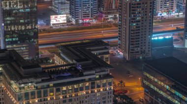 Dubai 'nin finans bölgesindeki oteller ve ofis binaları. Parlak pencereler ve gece aydınlatması. Caddelerde trafik