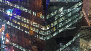 Yüksek katlı ofis kulesindeki pencereler gecenin geç saatlerinde parlayan ve yanıp sönen iç ışıkları olan. Havadan üst görünüm