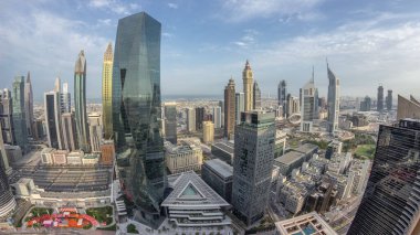 Sheikh Zayed karayolu zaman çizelgesinde Dubai 'deki finans bölgesi iş merkezindeki fütürist gökdelenlerin panoraması. Yukarıdan gökyüzü mavi bulutlu.