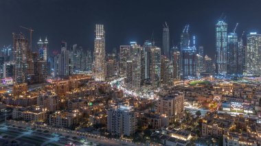 Dubai 'nin iş hanı ve şehir merkezindeki kuleler eski kasaba binalarıyla hava gece zaman ayarlı. Bazı gökdelenlerin çatı manzarası ve inşaat halindeki yeni kuleler